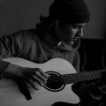 man in black knit cap playing acoustic guitar
