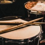 pair of brown wooden drumsticks on top of white and gray musical drum
